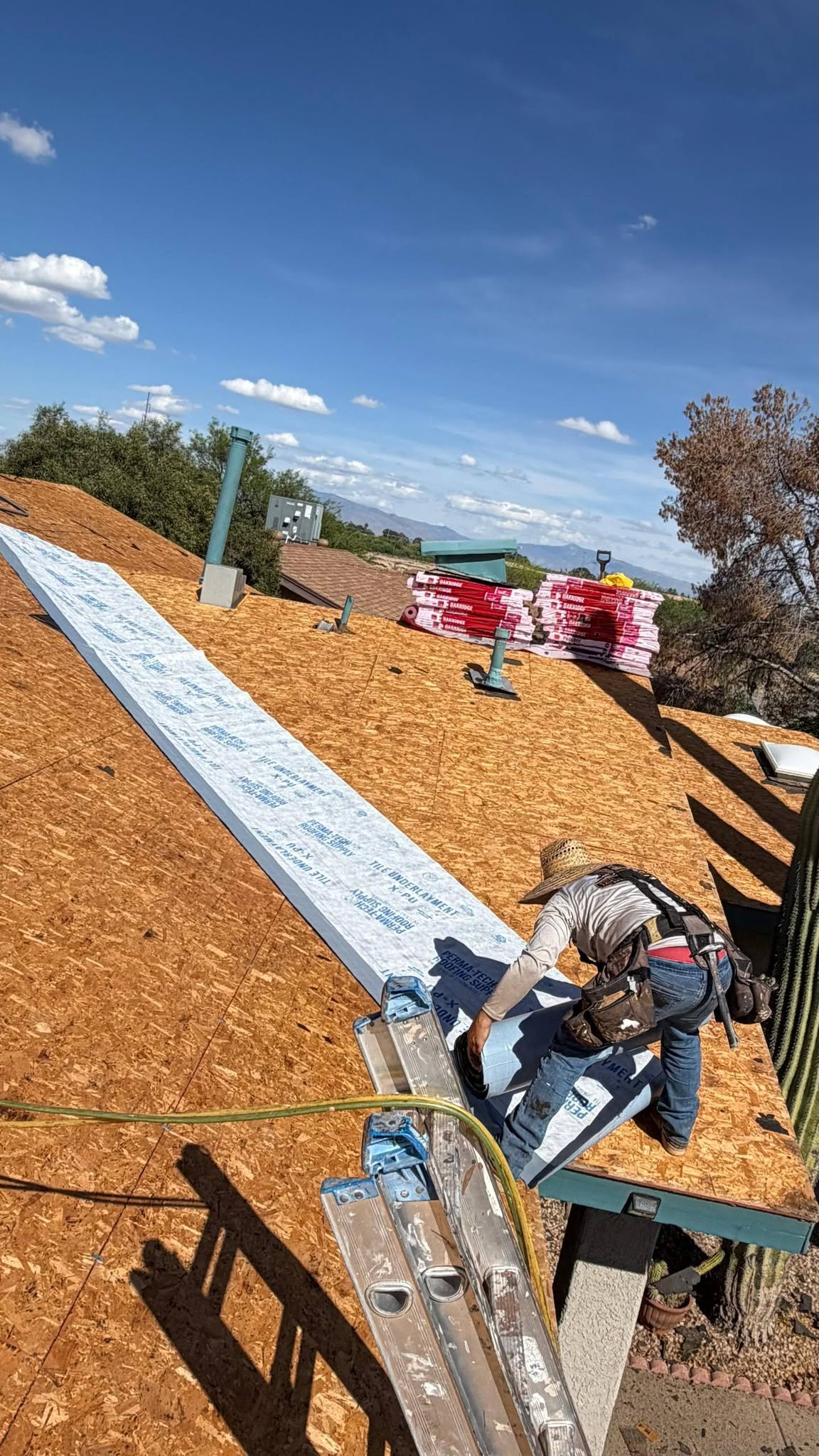 Grand Valley Roofing worker applying roofing underlayment on a residential roof.