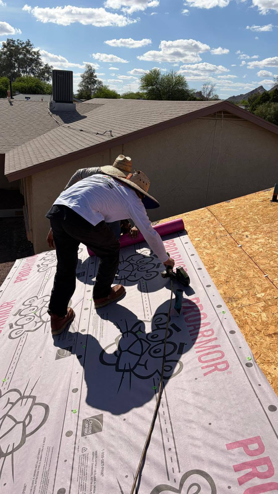 Grand Valley Roofing worker fastening roofing underlayment during a reroof.